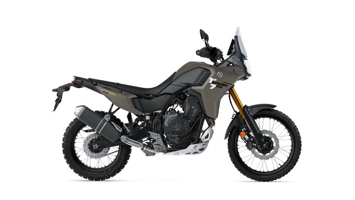 A side view of a Yamaha Ténéré 700 motorcycle, showcasing its rugged design, off-road tires, and a matte olive green finish. The bike features a sturdy frame, a high windshield, and a sleek exhaust system.