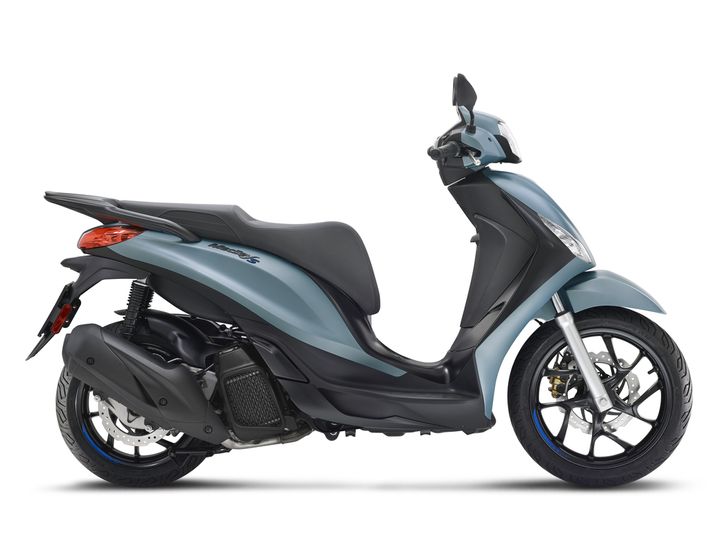 A sleek blue scooter viewed from the side, featuring a comfortable seat, sporty design, and modern details such as a front disc brake and sleek headlight.