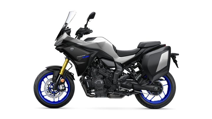 A side view of a Yamaha Tracer 9 GT motorcycle, featuring a sleek black body with blue accent wheels and a storage compartment on the rear.