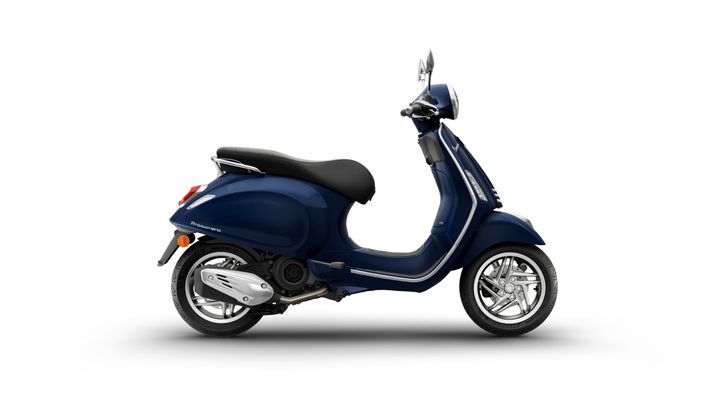 A sleek blue scooter with a comfortable black seat, showcasing a chrome-plated exhaust and stylish wheels, positioned on a white background.