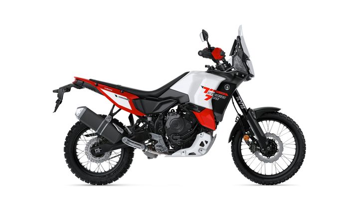 A Yamaha Ténéré 700 motorcycle in a side profile view, featuring a combination of red, black, and white colors, rugged tires, and off-road styling.