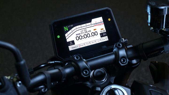 Close-up of a motorcycle's digital dashboard displaying various metrics including lap time, speed (0 km/h), time elapsed (00:00.00), temperature (26°C), and track settings.