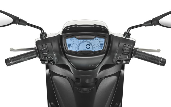 A close-up view of a motorcycle's dashboard, featuring a digital display showing speed, fuel gauge, and other metrics, with control buttons and grips on either side.