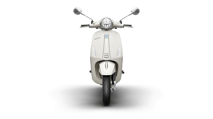 Front view of a cream-colored scooter with a sleek design, featuring round mirrors, a circular headlight, and a prominent logo. The scooter is set against a white background, highlighting its clean lines and modern aesthetics.