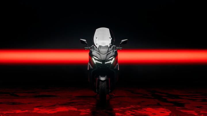 A sleek black motorcycle is positioned frontally against a dark backdrop, highlighted by a striking red light strip. The bike features a transparent windscreen and sharp LED headlights, emphasizing its modern design.