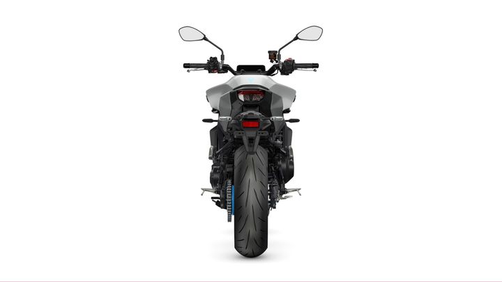 A rear view of a modern motorcycle, showcasing its wide tire, sleek body design, and handlebar controls against a plain white background.
