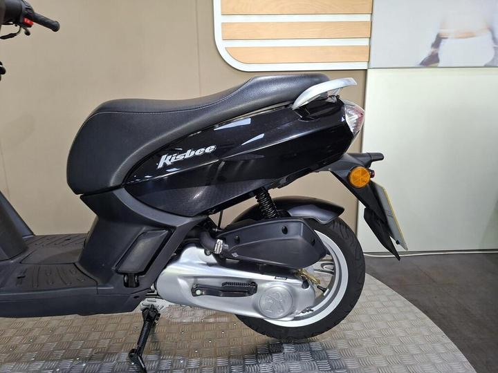 A black Kisbee scooter displayed on a patterned floor with a minimalist background.