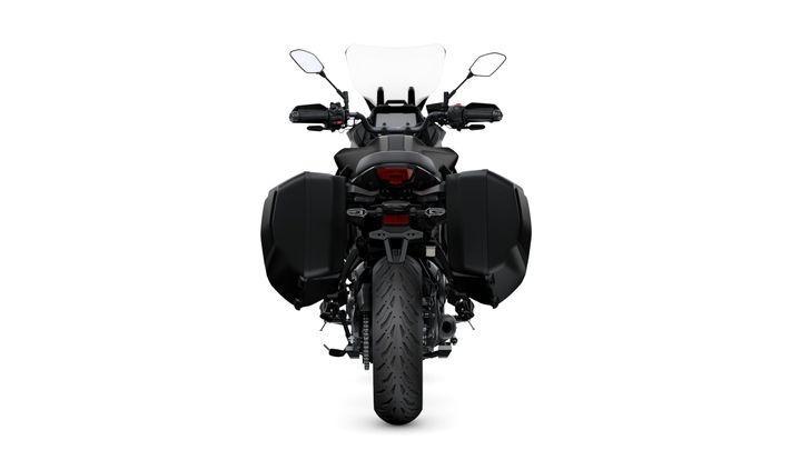 A rear view of a black motorcycle with side panniers, a visible rear tire, and a transparent windscreen. The handlebars feature mirrors and control switches.