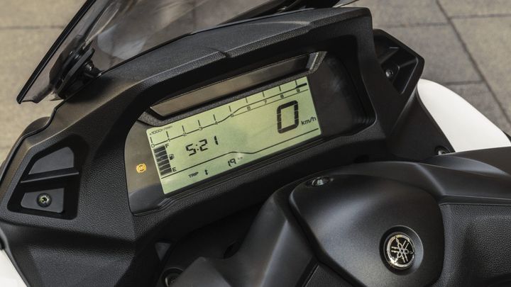 Close-up of a motorcycle dashboard displaying a digital speedometer, indicating 0 km/h, trip information showing 19 km, time reading 5:21, and various sensor indicators.