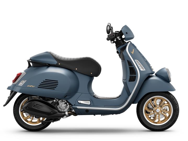 Vespa GTV 310 Officina 8 Euro 5+ A blue scooter with a retro design, featuring a black seat and gold wheels, positioned to showcase its side profile.
