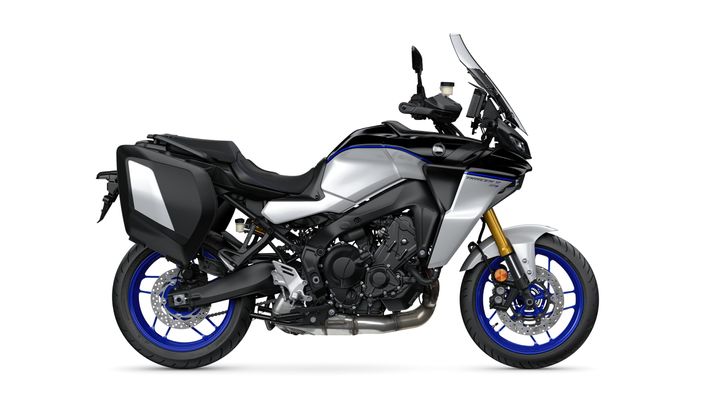 A side view of a modern sport touring motorcycle featuring a sleek black and silver design with blue accents and saddlebags.