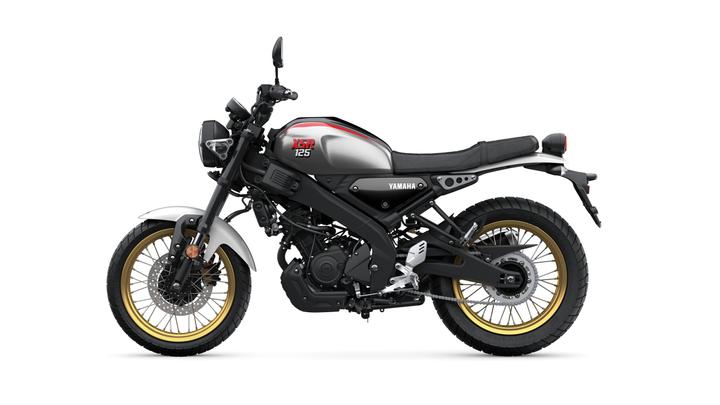 A sleek, modern Yamaha XSR125 motorcycle presented from a side view, showcasing its distinctive grey and black design, gold-accented wheels, and minimalist features.