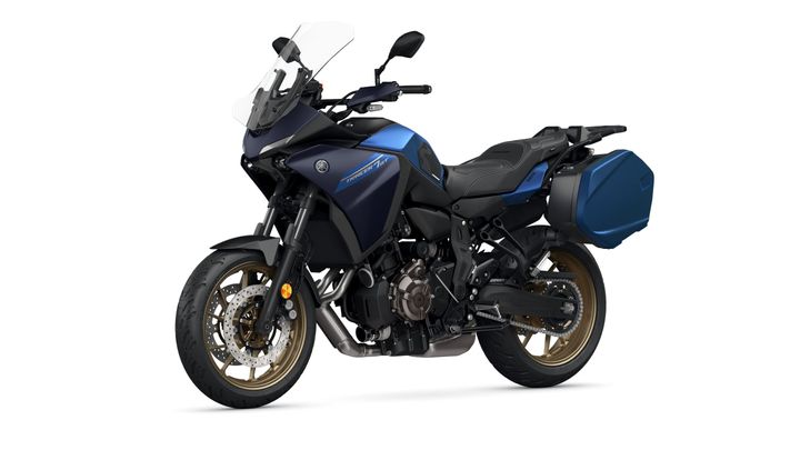 A blue and black Yamaha Tracer 9 GT motorcycle, featuring a sporty design, an adjustable windscreen, alloy wheels, and side luggage panniers, positioned on a white background.
