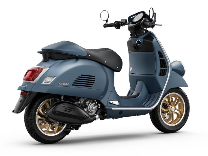 A vintage-style scooter in matte blue with gold accents and a comfortable black seat, showcasing sleek lines and modern features.