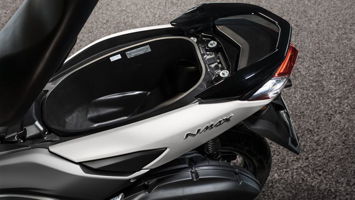 Close-up of the storage compartment of a Yamaha NMAX scooter, showing the interior and surrounding panels with a sleek design and brand logo.