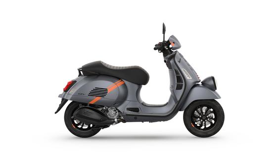 A modern gray scooter with orange accents, side view, featuring a stylish design and black wheels.