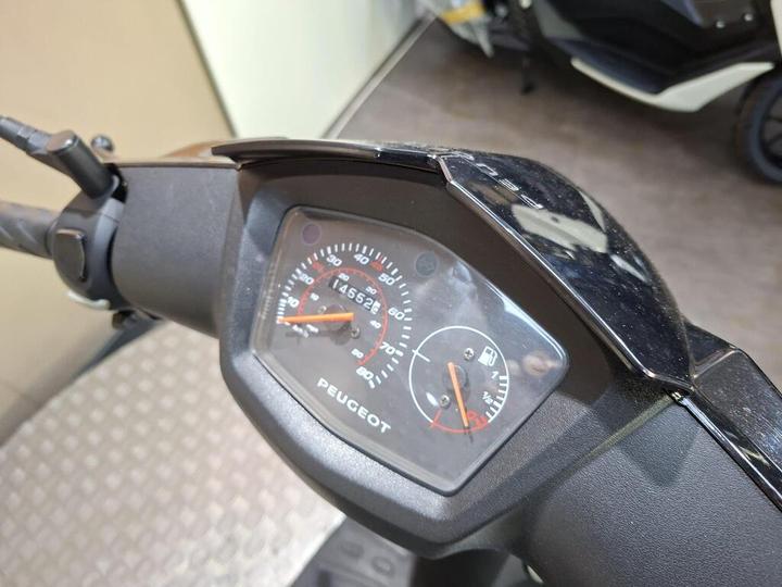 Close-up view of a Peugeot scooter's dashboard displaying the speedometer and fuel gauge, with a mileage reading of 14,522 kilometers.