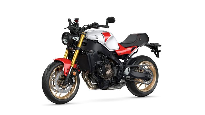 A stylish motorcycle with a white and red body, gold accents, and a modern design, featuring a round headlight and a sporty seat.