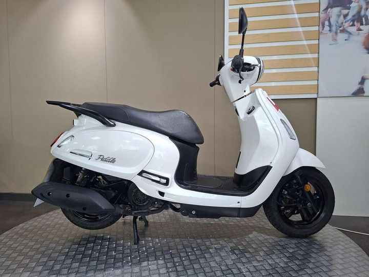 SYM Fiddle 125 2020 A white scooter is displayed on a checkered surface, showcasing its sleek design, black seat, and rear view mirror against a neutral backdrop.