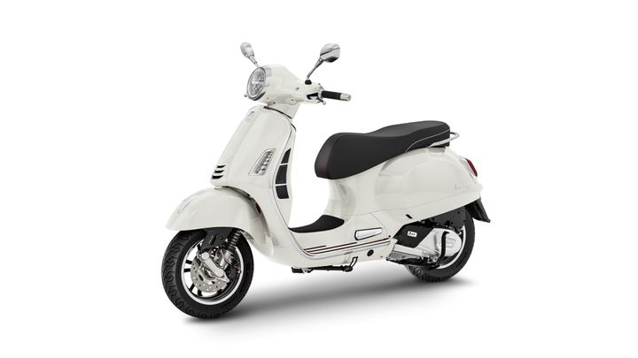 A sleek white scooter with a black seat, featuring classic design elements like a rounded headlight and chrome accents, positioned at a slight angle against a white background.