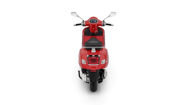 A red scooter viewed from the rear, featuring a sleek design, a black seat, and chrome accents. The handlebars have mirrors and a digital display.