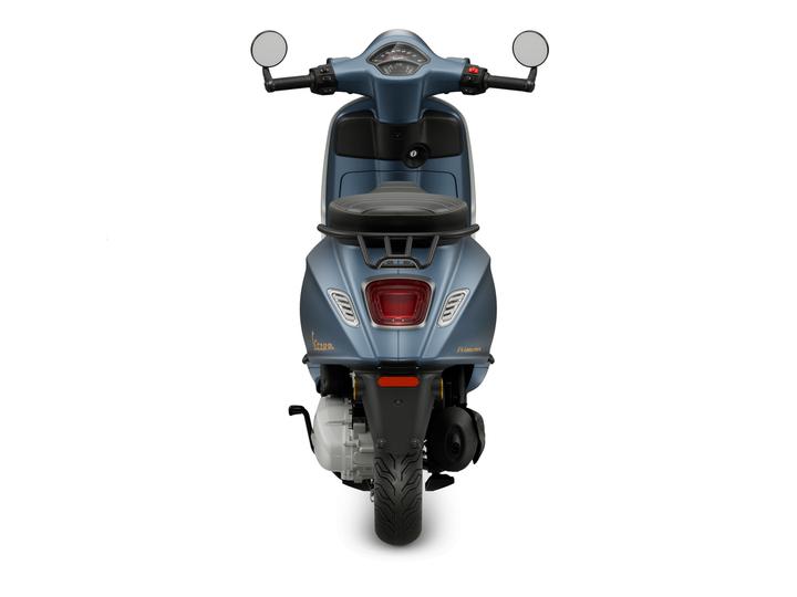 A blue scooter viewed from the rear, featuring a black seat, rear headlights, and a visible exhaust.