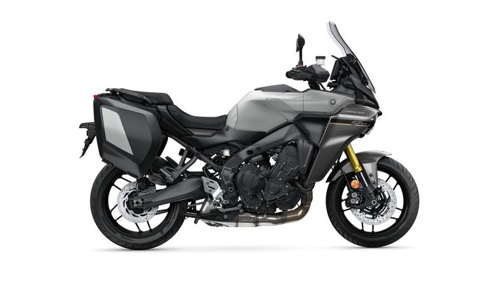 A sleek gray motorcycle with a sturdy build, featuring a high windshield, side luggage compartments, and a muscular engine design, parked on a plain white background.