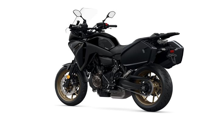 A sleek, black adventure motorcycle with gold wheels, featuring a tall windscreen, dual headlights, and side luggage compartments.