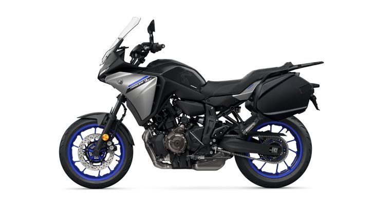 A side view of a black and silver Yamaha motorcycle with blue accents, featuring a sporty design, visible engine components, and a luggage box on the rear.