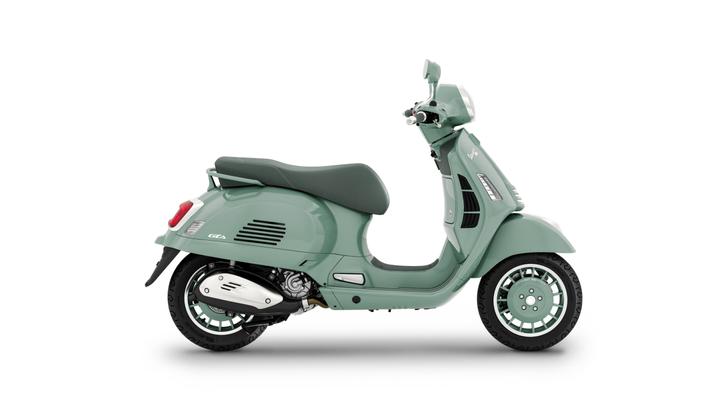 A mint green vintage-style scooter is shown in profile, displaying its sleek design, round headlight, and comfortable seat. The scooter features chrome accents and distinctively patterned wheels.