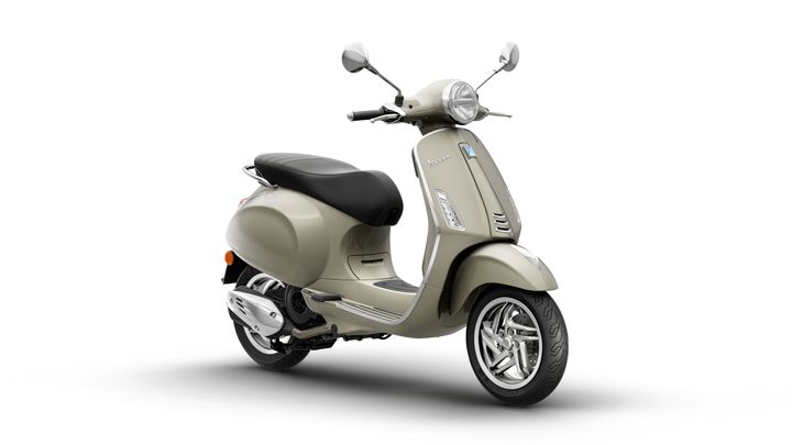 A vintage-style beige scooter, angled to show its sleek design, black seat, and chrome accents, set against a white background.