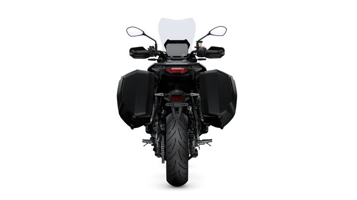 A rear view of a black motorcycle with side panniers and a tall windshield, showcasing the sleek design and rear tire.