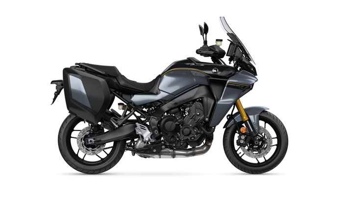 A side view of a sleek gray motorcycle with a sporty design, featuring a large windshield, black side panniers, and gold accents on the front suspension.