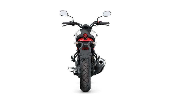 A rear view of a motorcycle, showcasing its sleek tail light, exhaust, and wide rear tire against a plain white background.