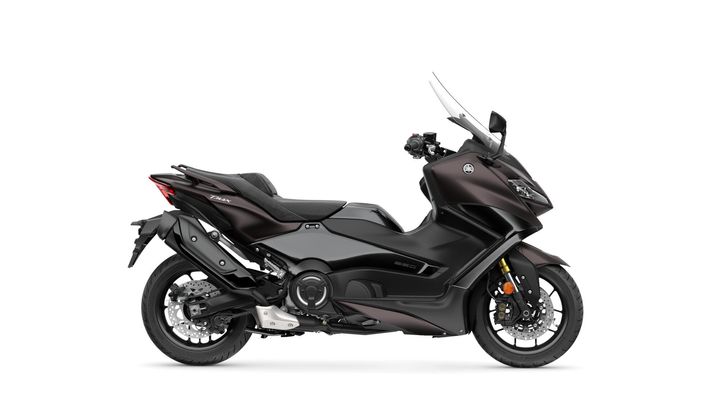 A sleek, dark gray Yamaha TMAX scooter with a sporty design, featuring a large windscreen, dual headlights, and a comfortable seat. The scooter is shown from the side, highlighting its smooth curves and modern aesthetics.