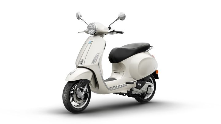 A sleek, white scooter with a retro design, featuring a round headlight, black seat, and chrome accents, positioned on a clean white background.