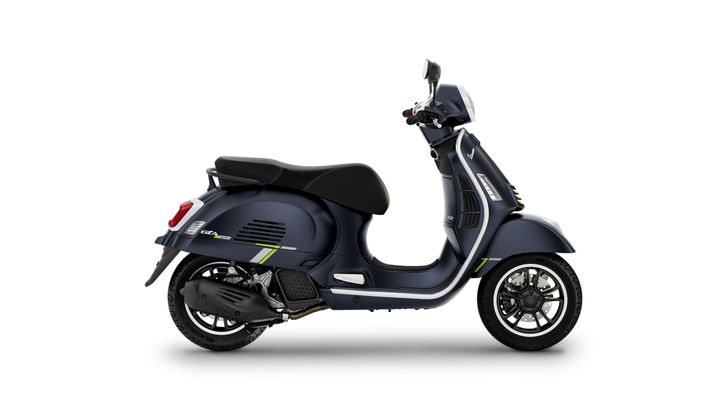 A sleek navy blue scooter with green accents, featuring a comfortable black seat, modern design elements, and sporty wheels, positioned in profile against a white background.