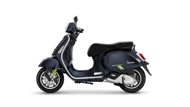 A dark blue Vespa scooter with green accents, viewed from the side, showcasing its sleek design and modern features.