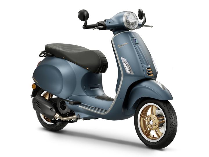 A sleek blue scooter with a black seat and golden wheels, featuring a classic design and modern details, positioned against a white background.