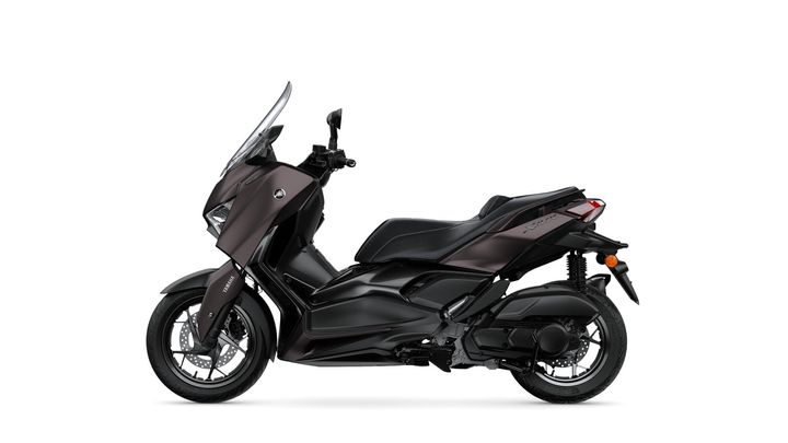 A sleek, dark-colored scooter is shown from the side, featuring a modern design, a windshield, and comfortable seating, set against a plain white background.