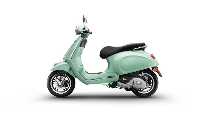A mint green scooter with a sleek design, featuring a black seat, chrome accents, and a distinctive front light, positioned against a white background.