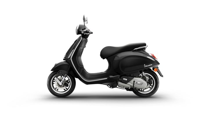 A sleek black Vespa scooter positioned at an angle, showcasing its streamlined design and chrome accents against a white background.