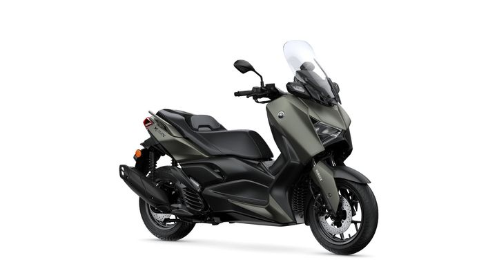 A modern scooter, the Yamaha XMAX, featuring a sleek design with an olive green and black color scheme, a tall windscreen, and alloy wheels, positioned on a white background.