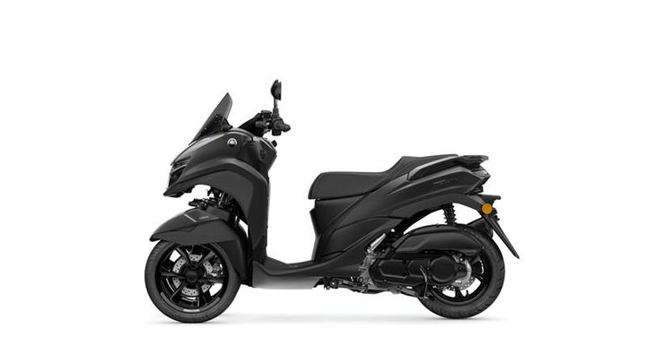A sleek black scooter is shown from the side, featuring a windscreen, comfortable seat, and modern design elements. The front wheel is prominently displayed, and the overall look is sporty and compact.