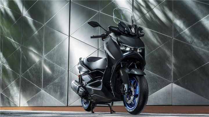 A sleek black motorcycle with blue accents standing against a geometric metallic background.