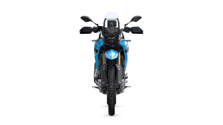 A blue adventure motorcycle viewed from the front, showcasing its distinctive headlight design, windscreen, handlebars, and off-road tires.