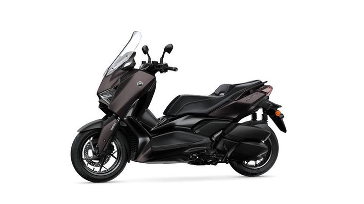 A sleek, modern scooter in a dark metallic color, featuring a tall windscreen, streamlined body design, and a comfortable seat, shown at an angle against a plain background.