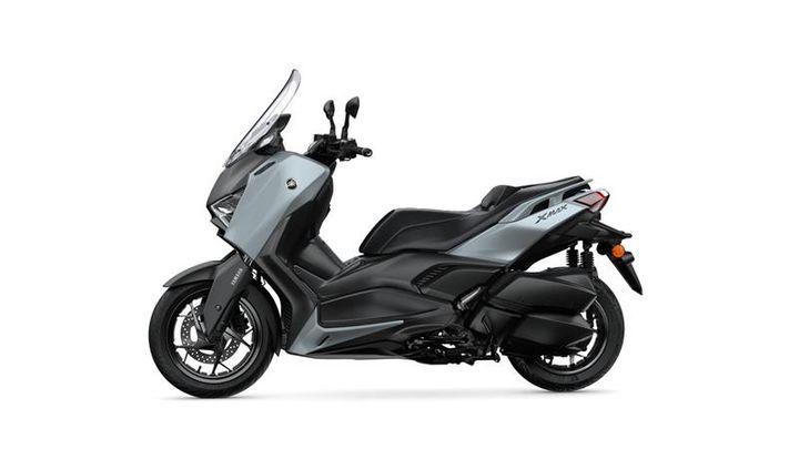 A sleek, modern scooter, the Yamaha XMAX, is shown in profile, featuring a two-tone gray and black design, large windscreen, and a sporty silhouette.