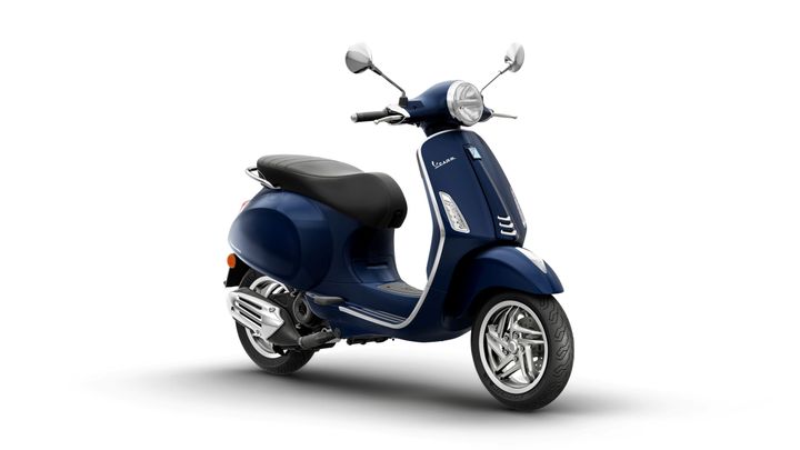 A modern blue Vespa scooter with a black seat, chrome accents, and a classic design, positioned on a white background.