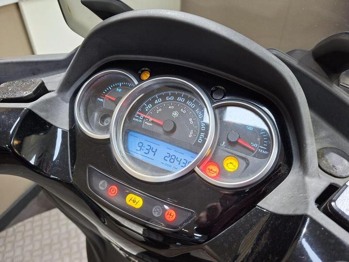 Dashboard of a motorcycle displaying various gauges, including speedometer, fuel level, and temperature, with a digital clock reading 9:34 and an odometer showing 28473.